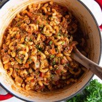 Goulash in a Dutch oven pot with a wooden spoon.