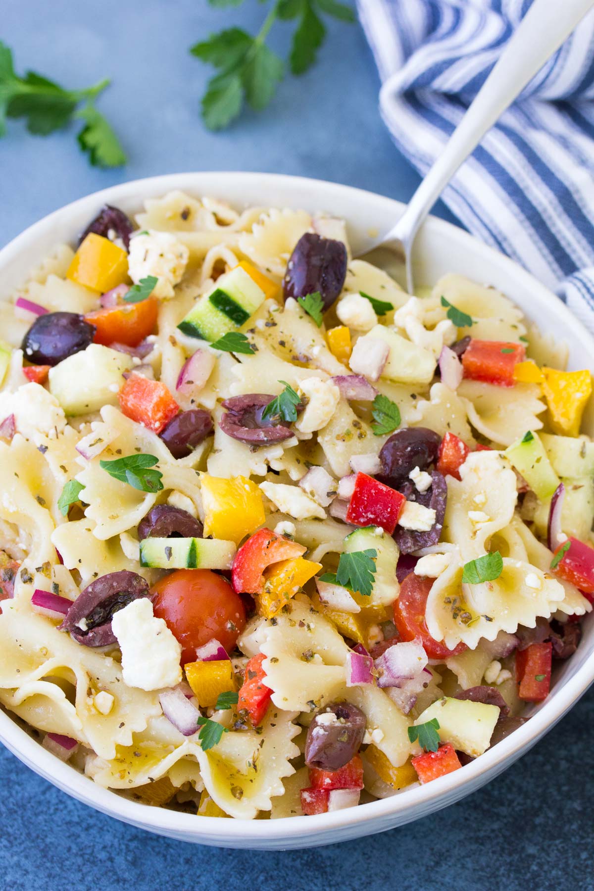 Greek pasta salad in a bowl with a serving spoon.