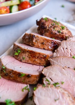 Sliced grilled pork tenderloin on a rectangular plate.