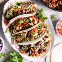 Four ground turkey tacos next to each other on a plate.