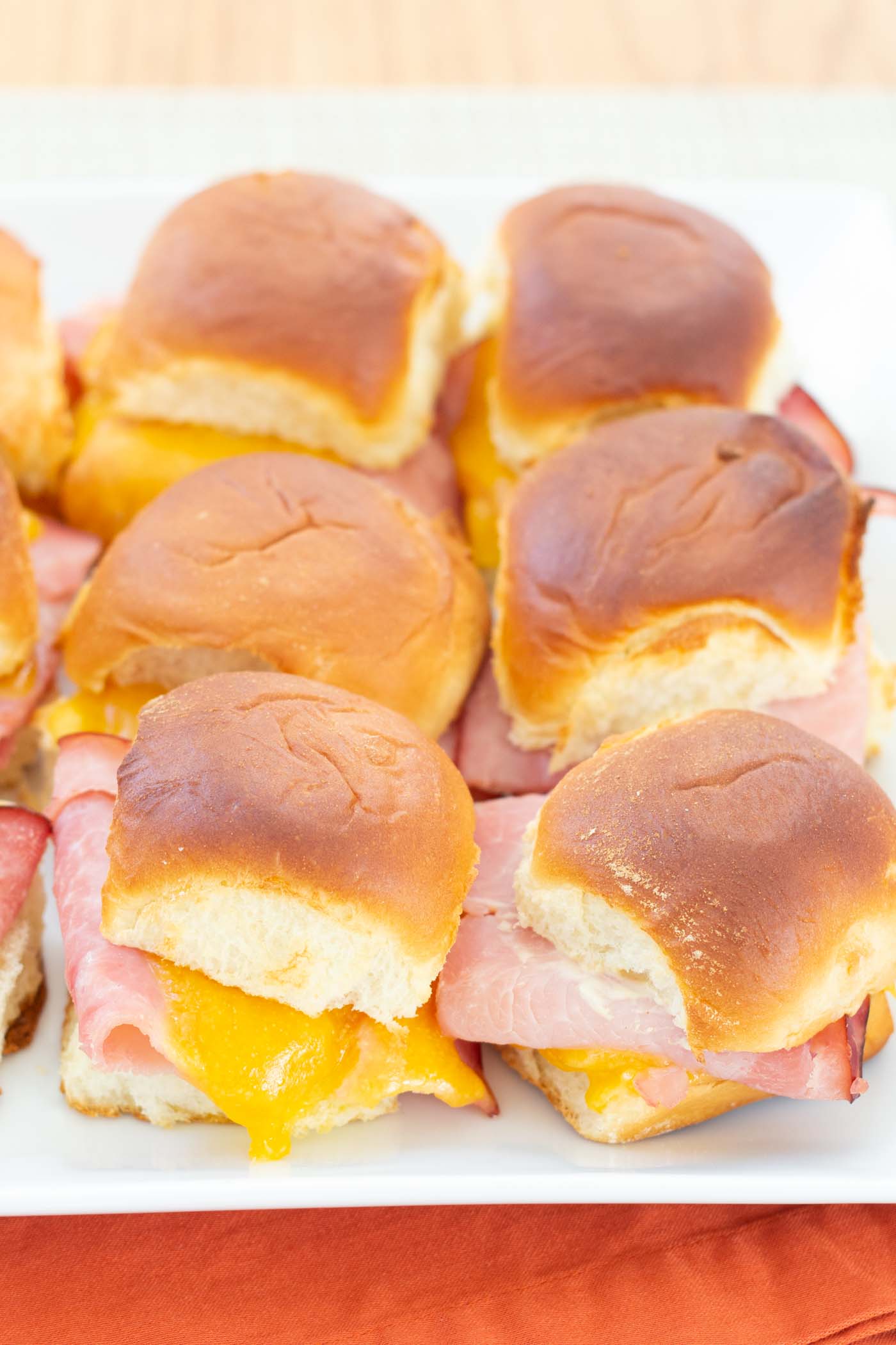 Ham and cheddar sliders on a serving plate.