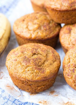 Healthy banana muffins on parchment paper with cinnamon sprinkled around.