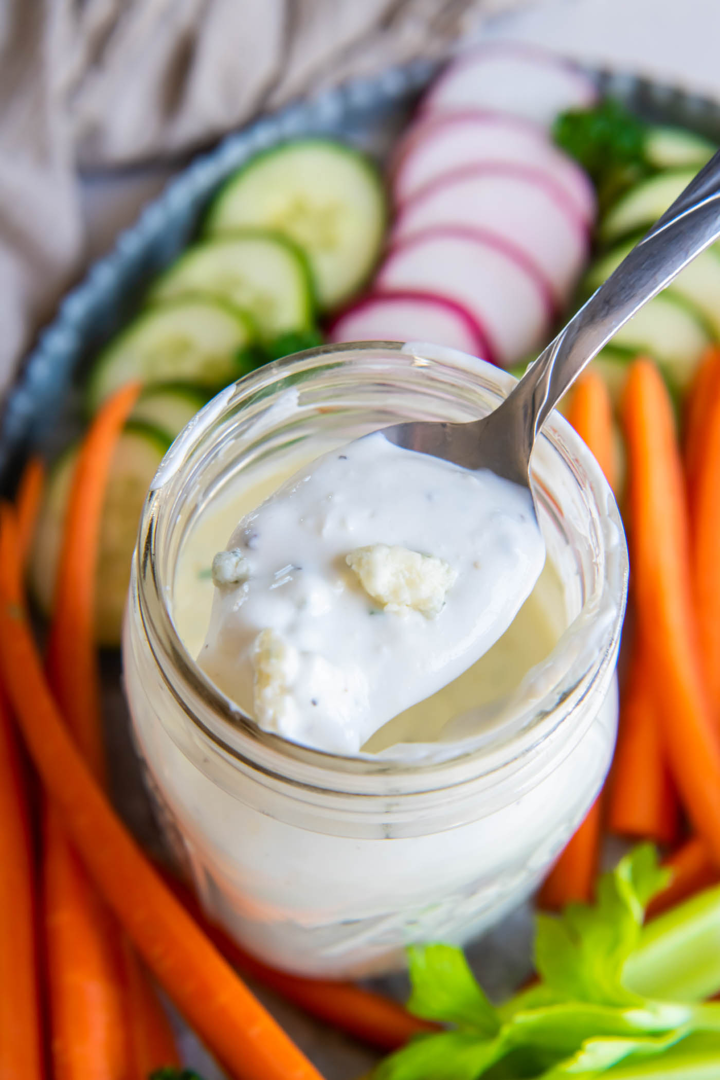 Blue cheese dressing on a spoon held over jar of dressing.