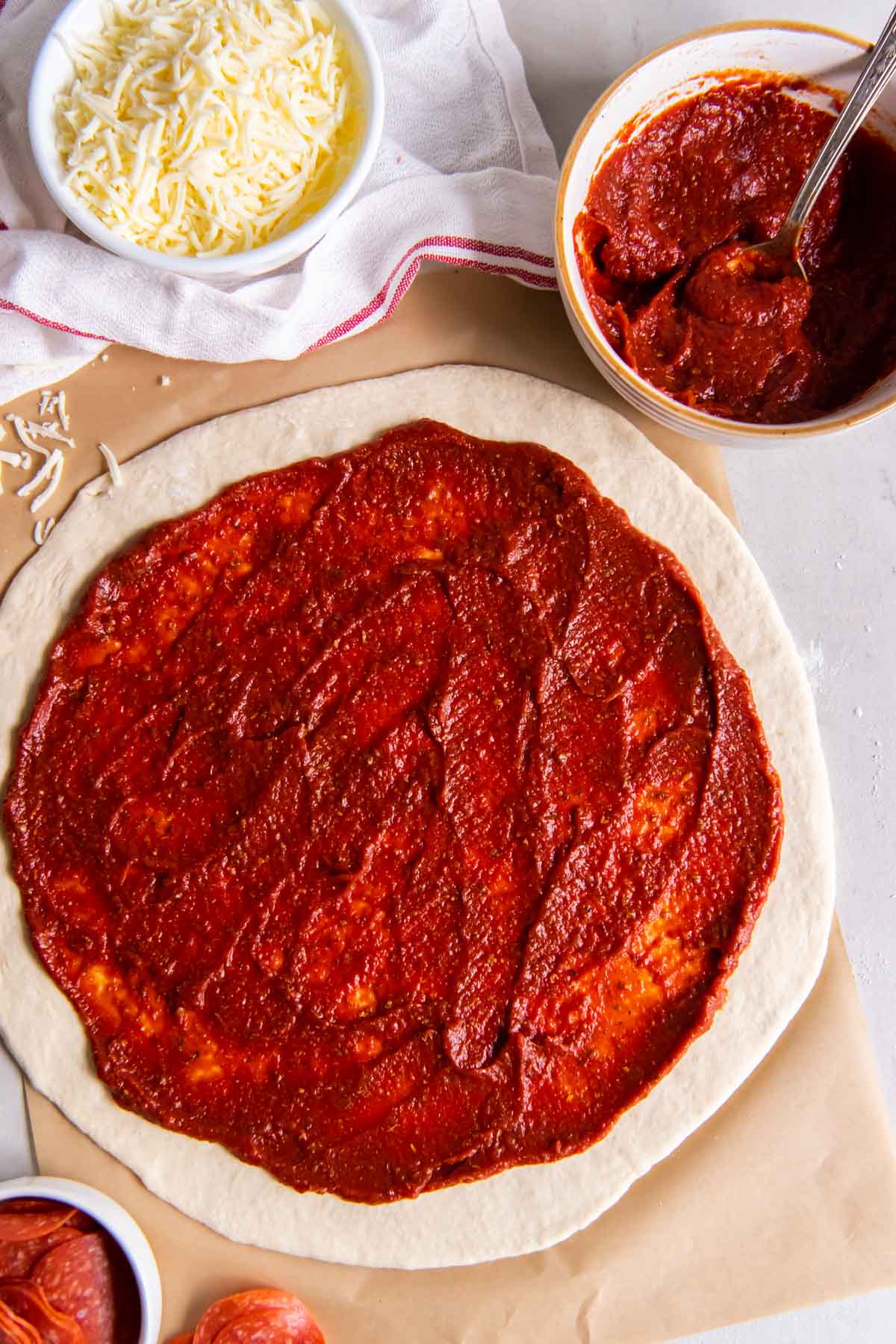Pizza sauce spread over rolled out pizza dough.
