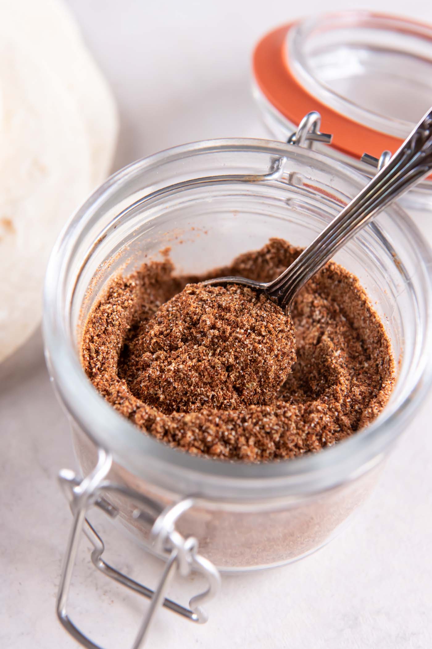 Taco seasoning in a jar with a spoon.