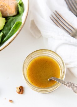Honey mustard dressing in a small glass jar with a spoon.