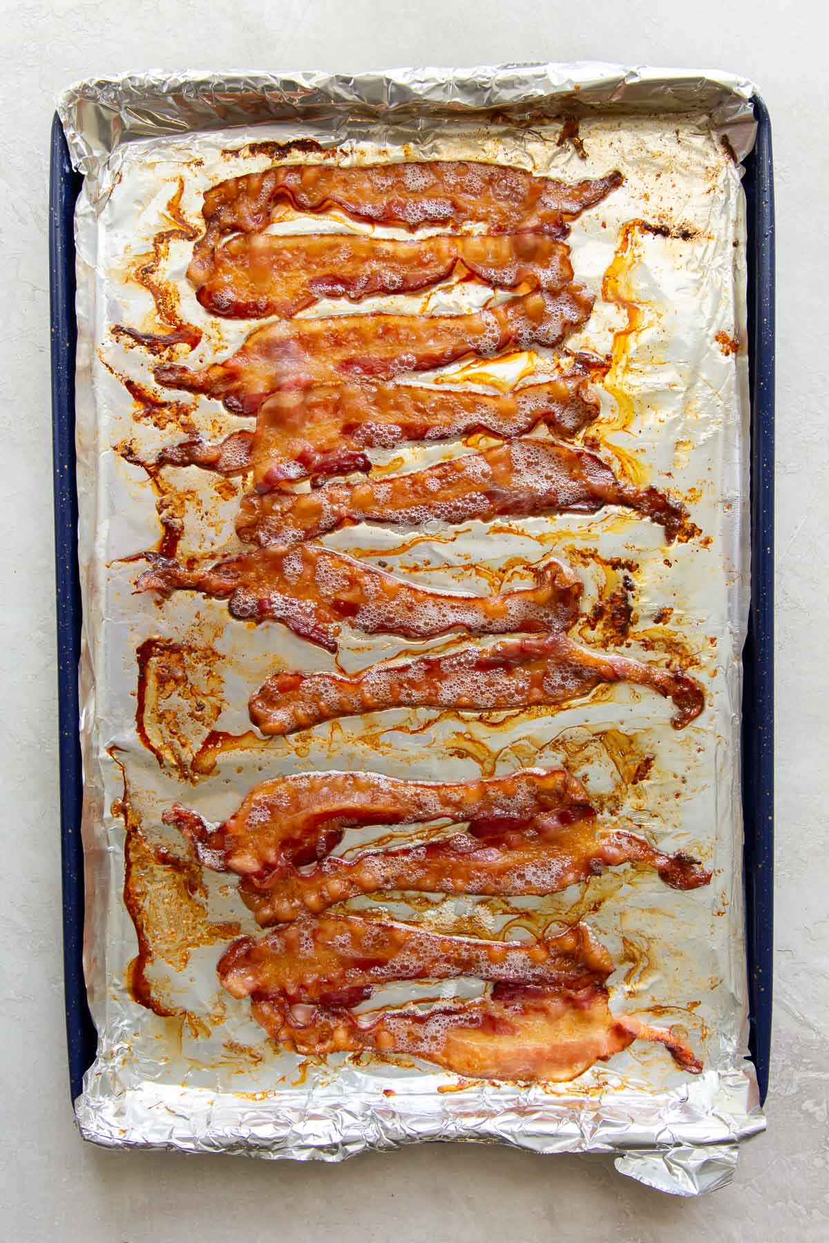 baked bacon slices on a foil-lined rimmed baking sheet