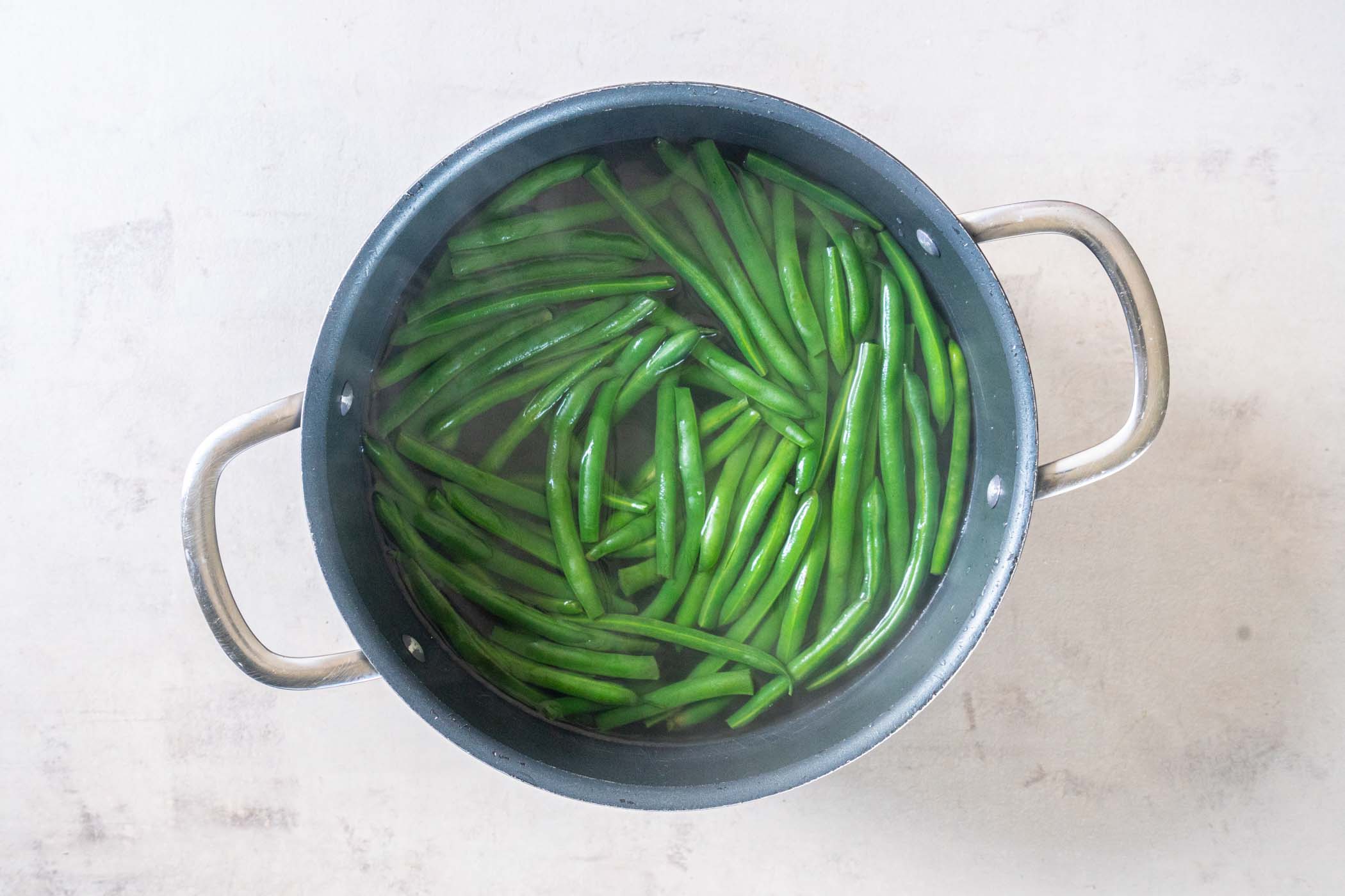 Boiled green beans in pot of water.