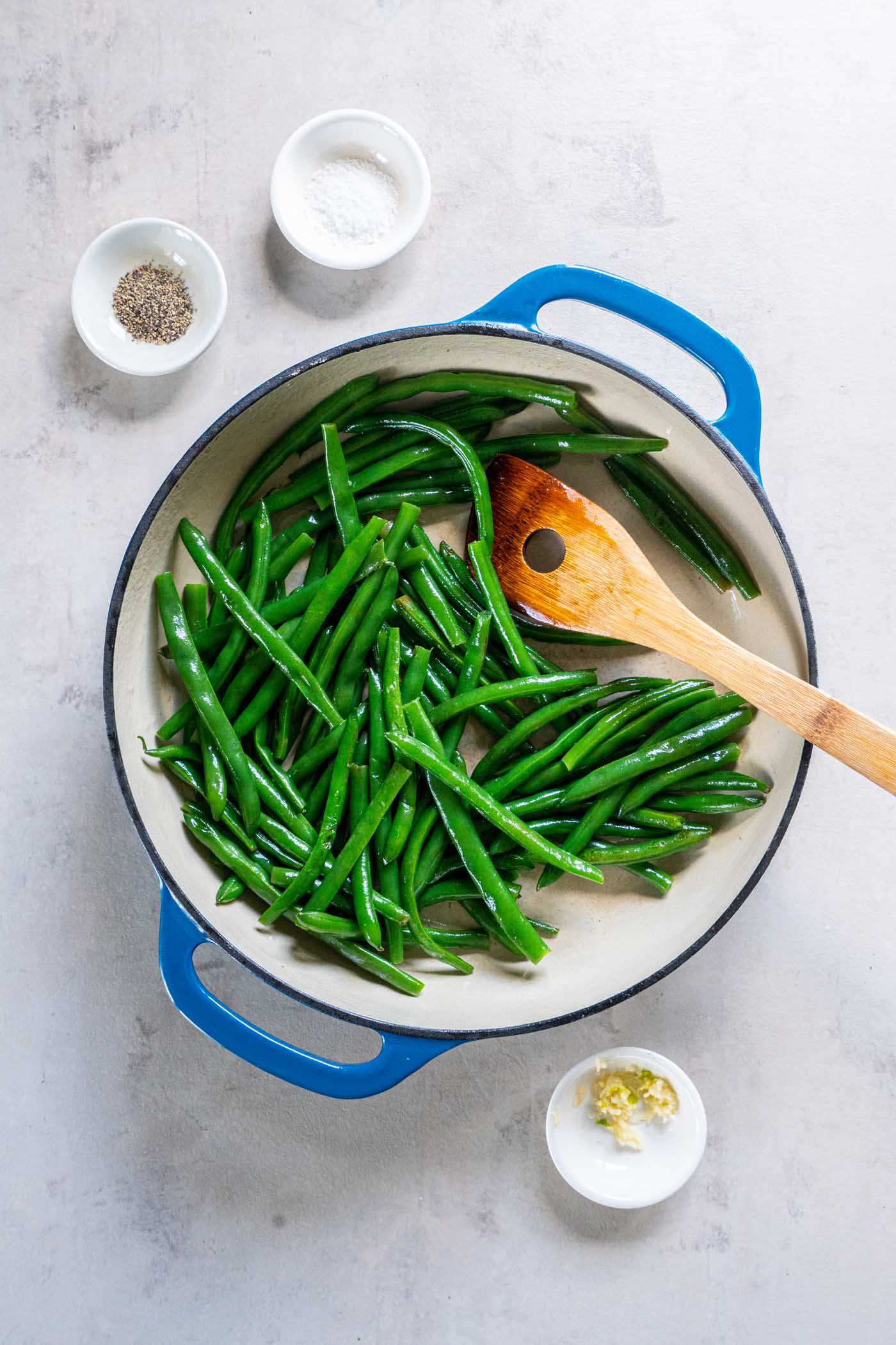 Sautéing green beans in skillet with a wooden spoon.