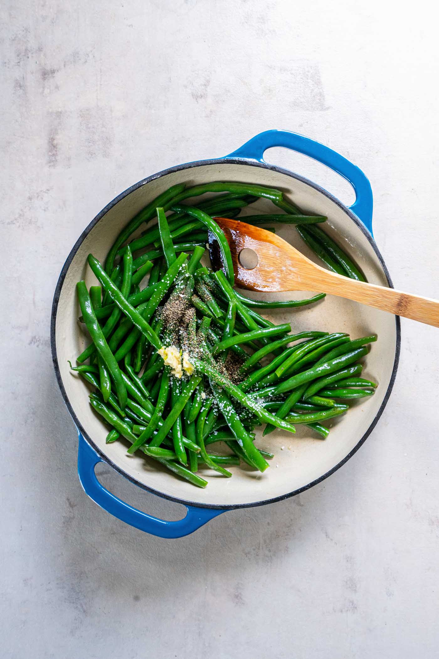 Minced garlic, salt and pepper added to green beans in skillet.