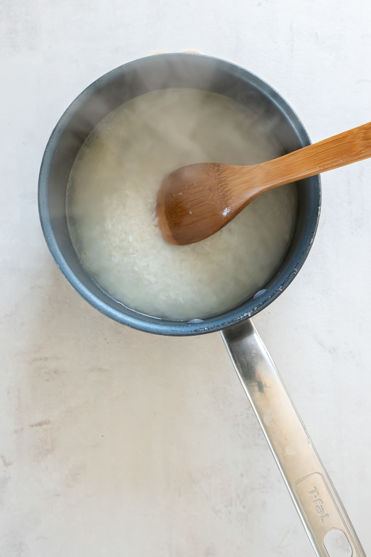 Stirring rice into water in pot.