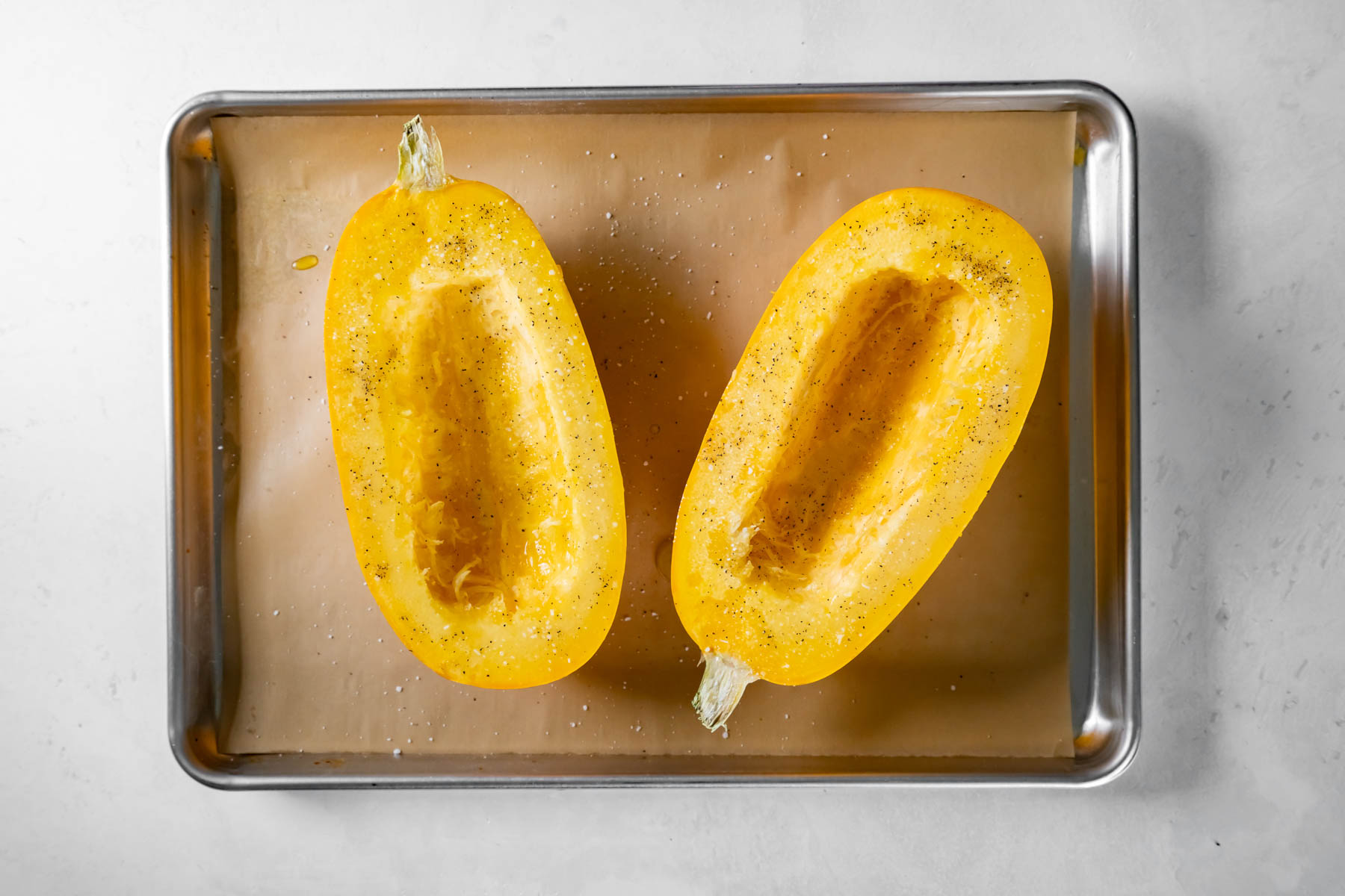 two spaghetti squash halves with olive oil, salt and pepper