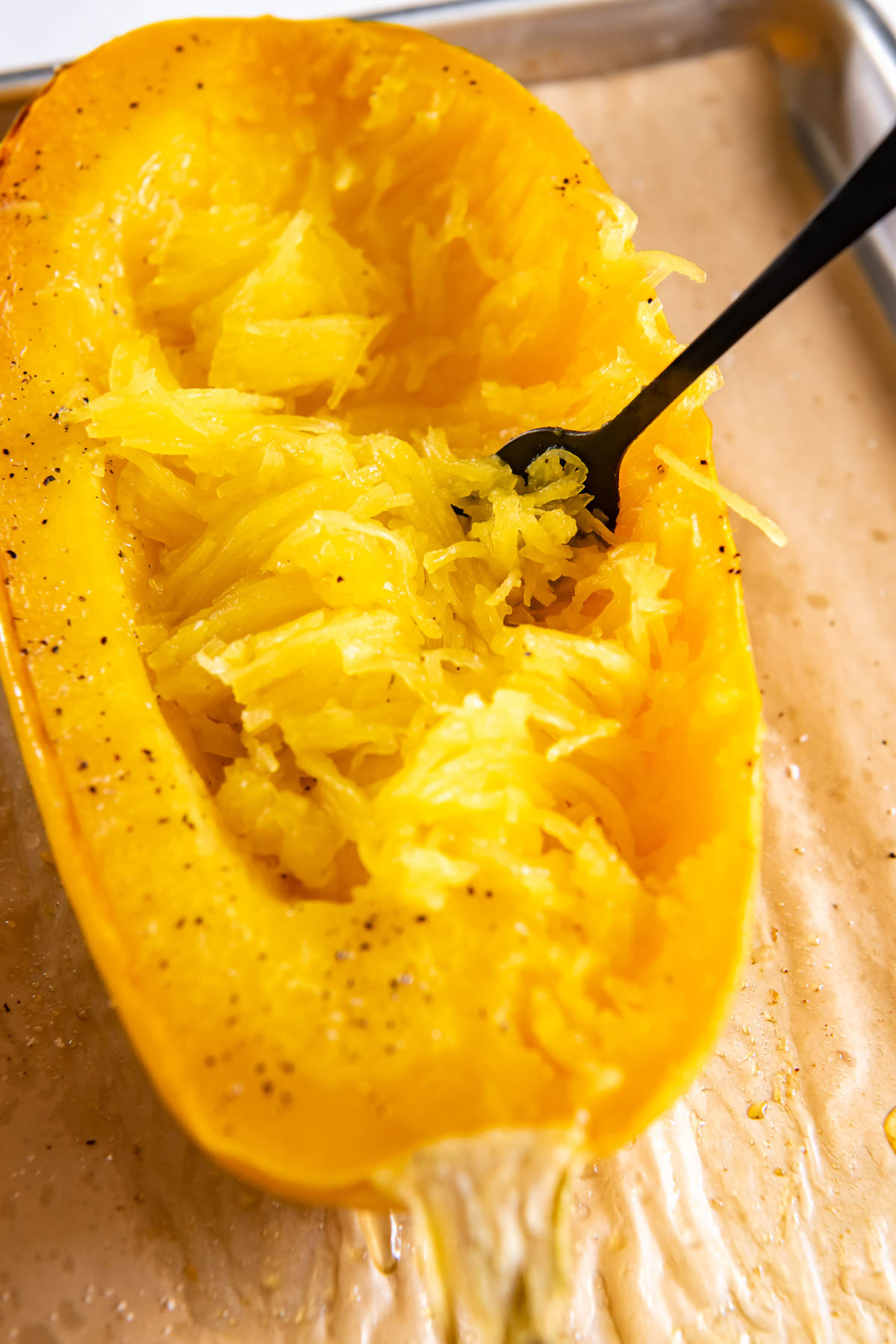 half spaghetti squash separated into strands with fork