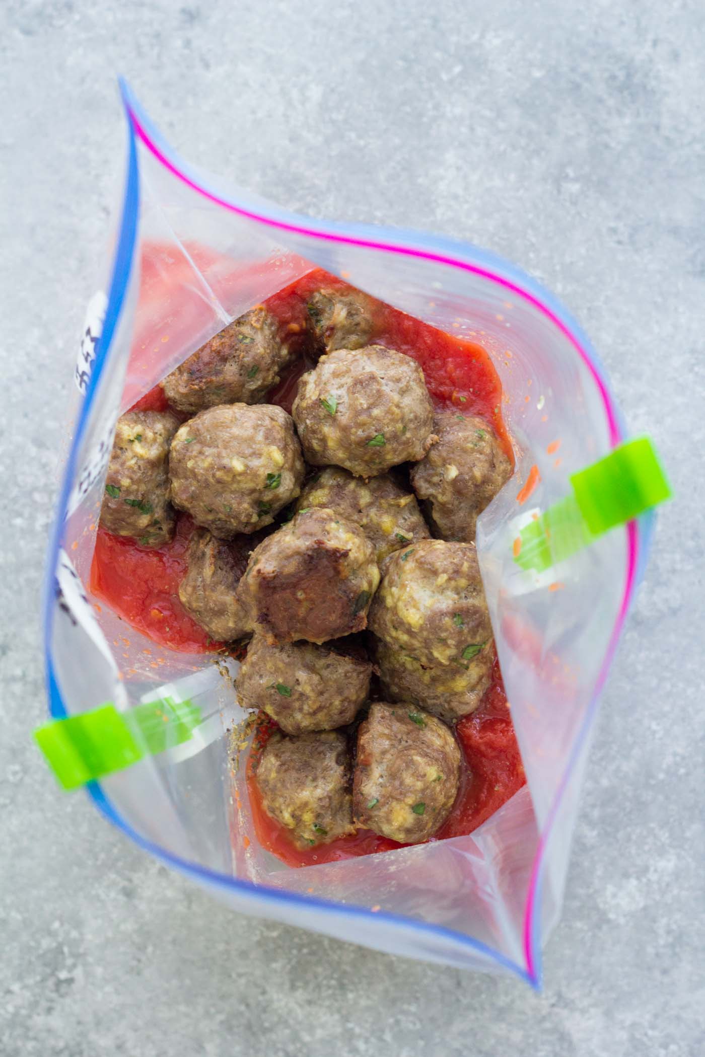 Baked meatballs in a zip-top bag with marinara sauce ingredients.
