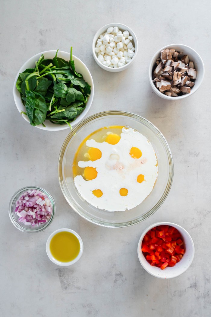 Eggs, milk and salt in a mixing bowl with other frittata ingredients around.