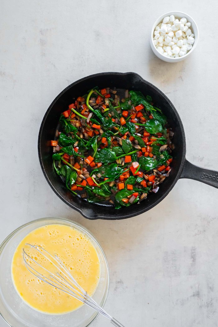 Wilted spinach and sauteed vegetables in skillet.