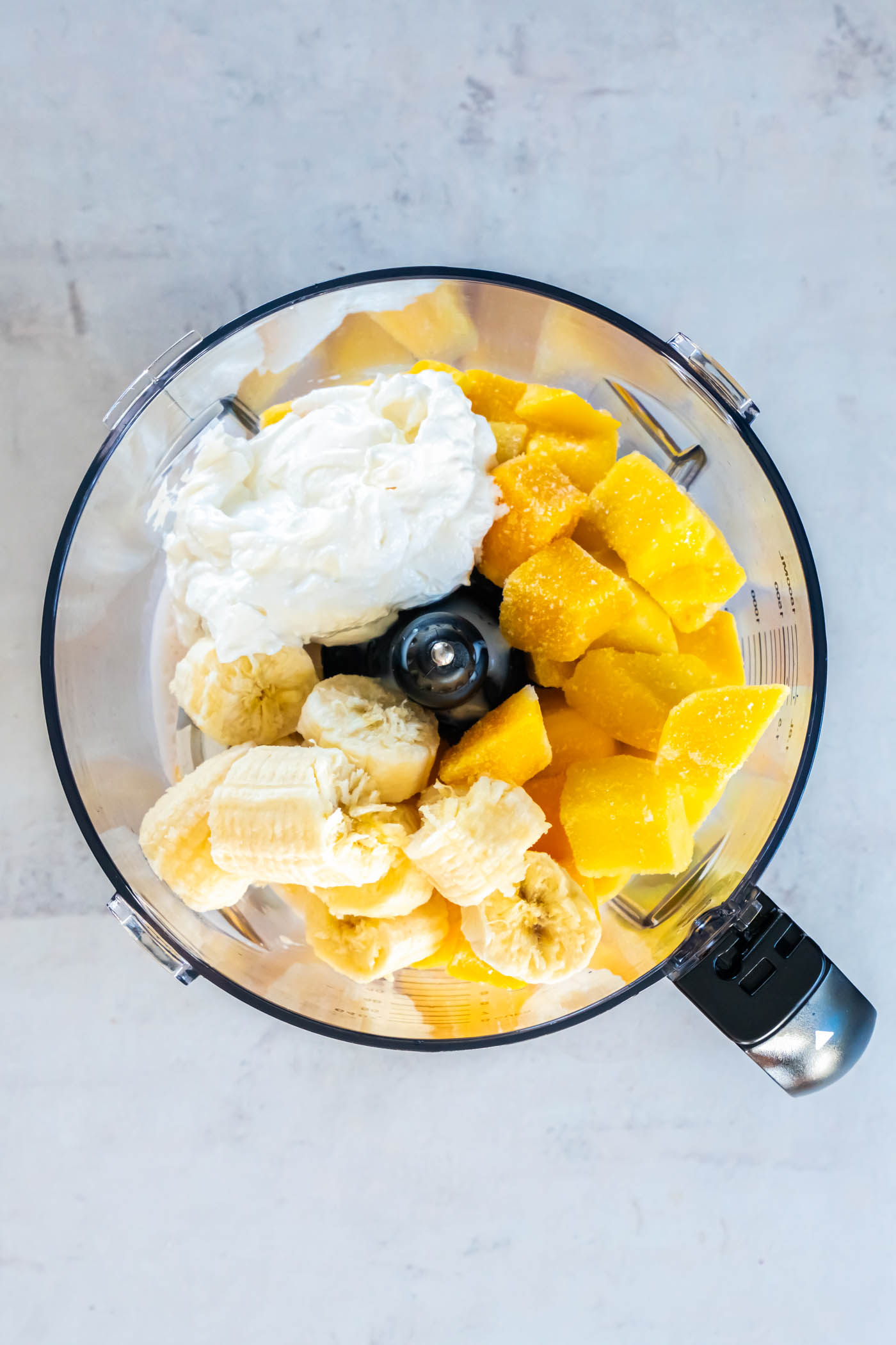Frozen mango, banana, Greek yogurt and almond milk in a blender.