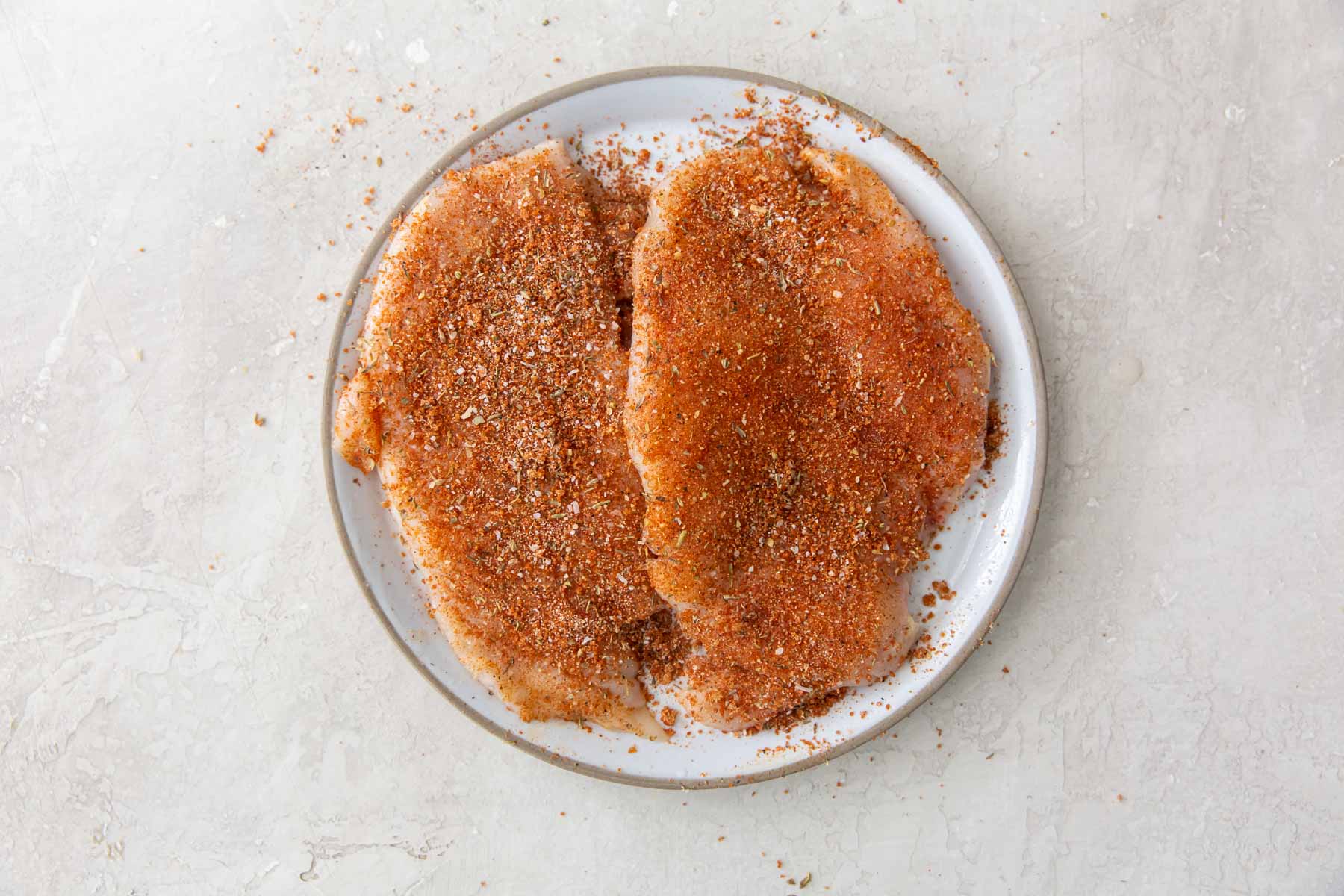 two boneless skinless chicken breasts rubbed with seasoning rub
