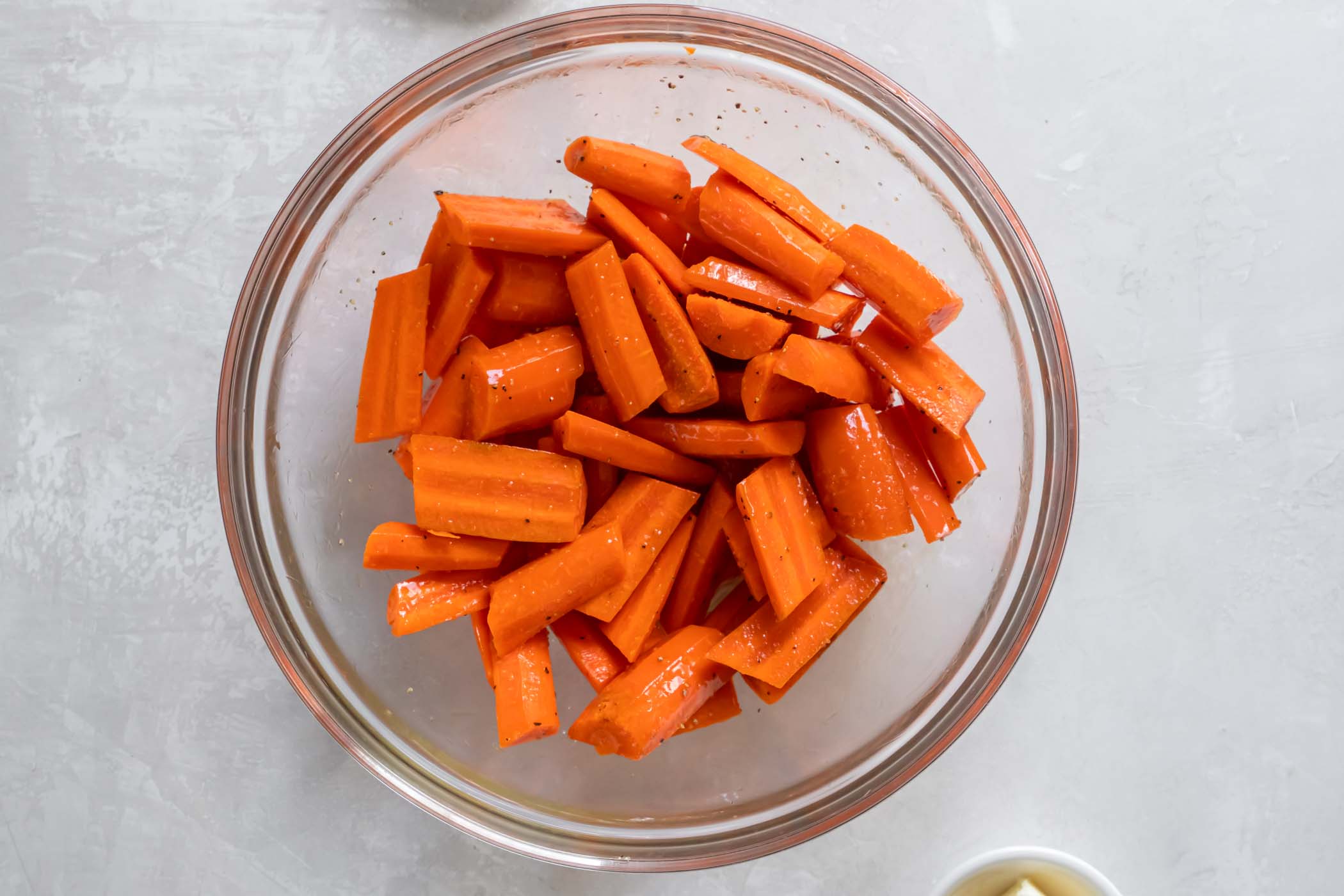 Chopped carrots in a bowl tossed with olive oil, salt and pepper.
