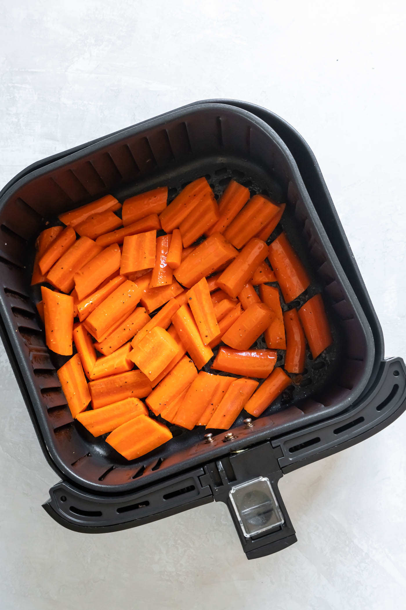 Uncooked chopped carrots in air fryer.