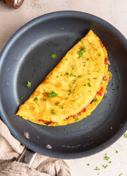 Omelet with bell pepper, red onion and cheese in a nonstick skillet.