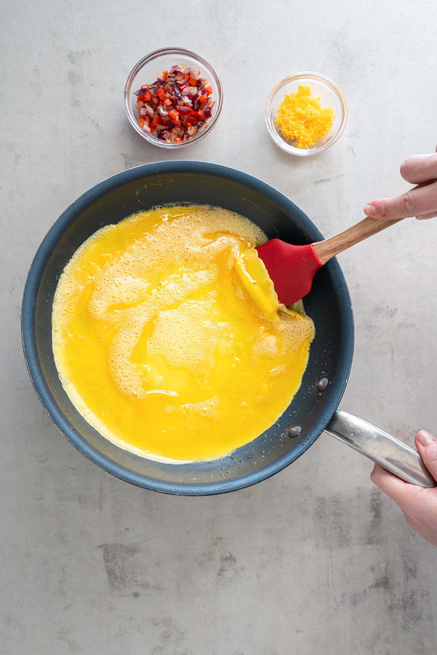 Lifting up side of omelet with spatula to let wet eggs run underneath.