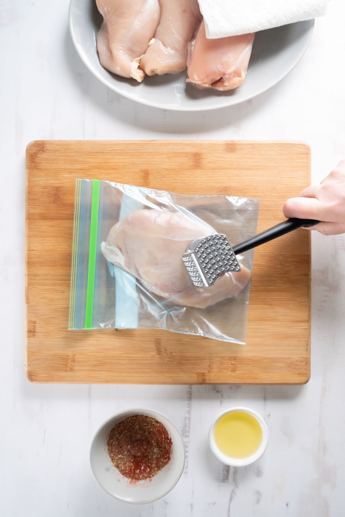Pounding chicken breast with meat mallet.