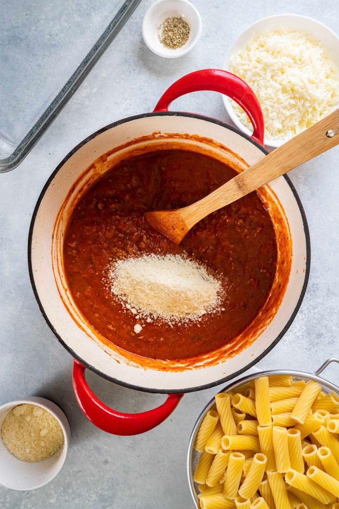 Grated Parmesan cheese added to meat sauce in pot.