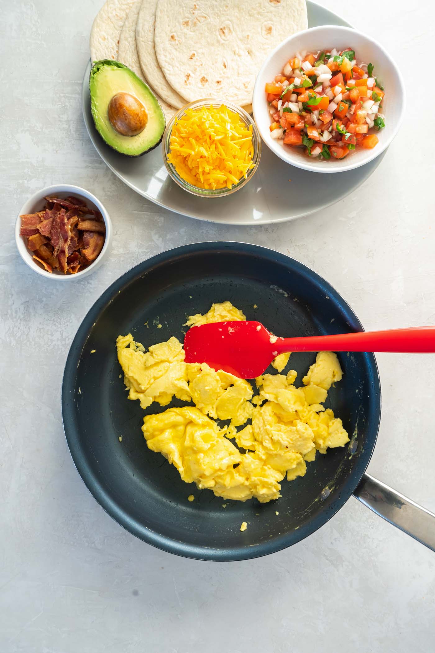 Scrambled eggs in pan with spatula.