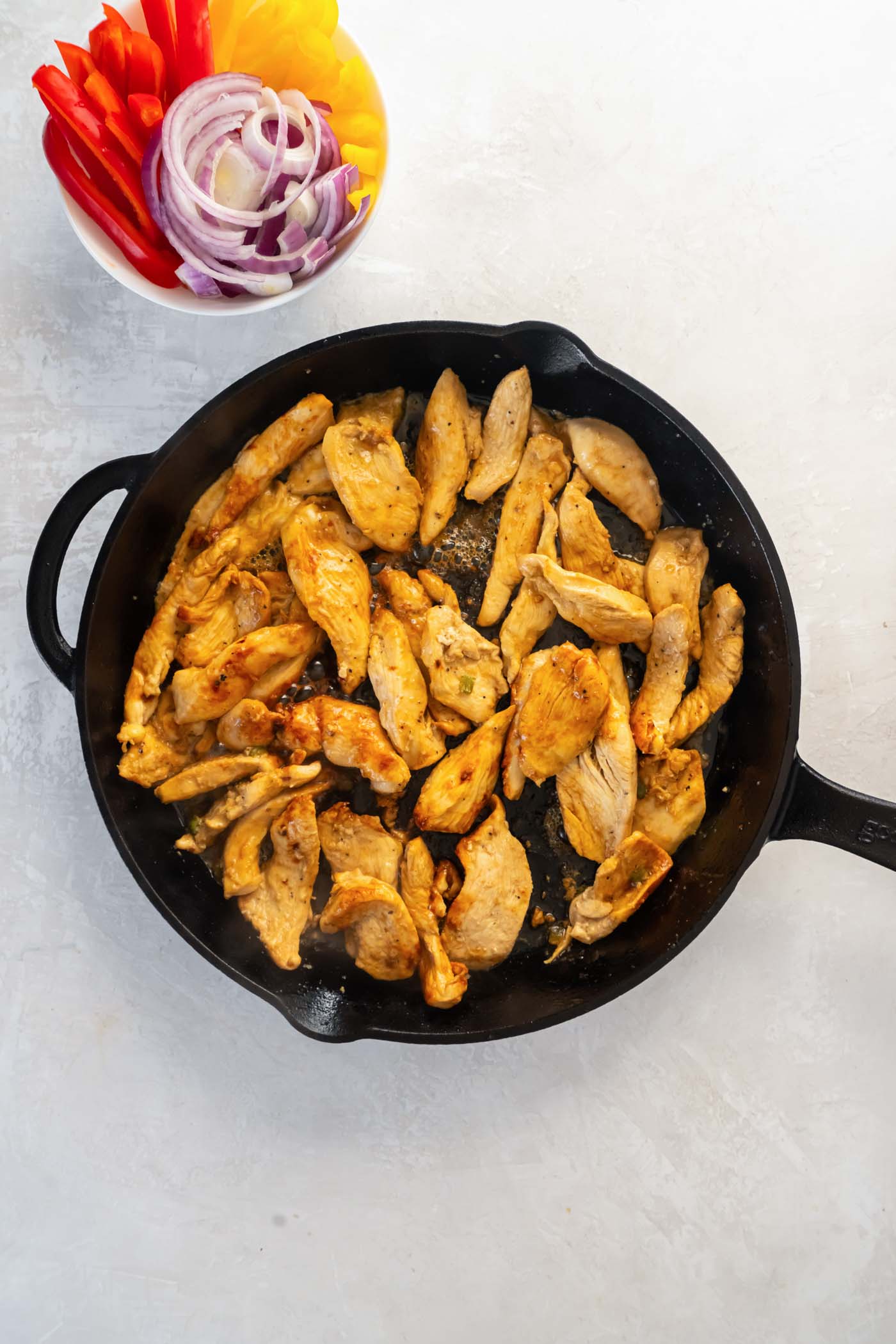 Cooking marinated chicken pieces in a cast iron skillet.
