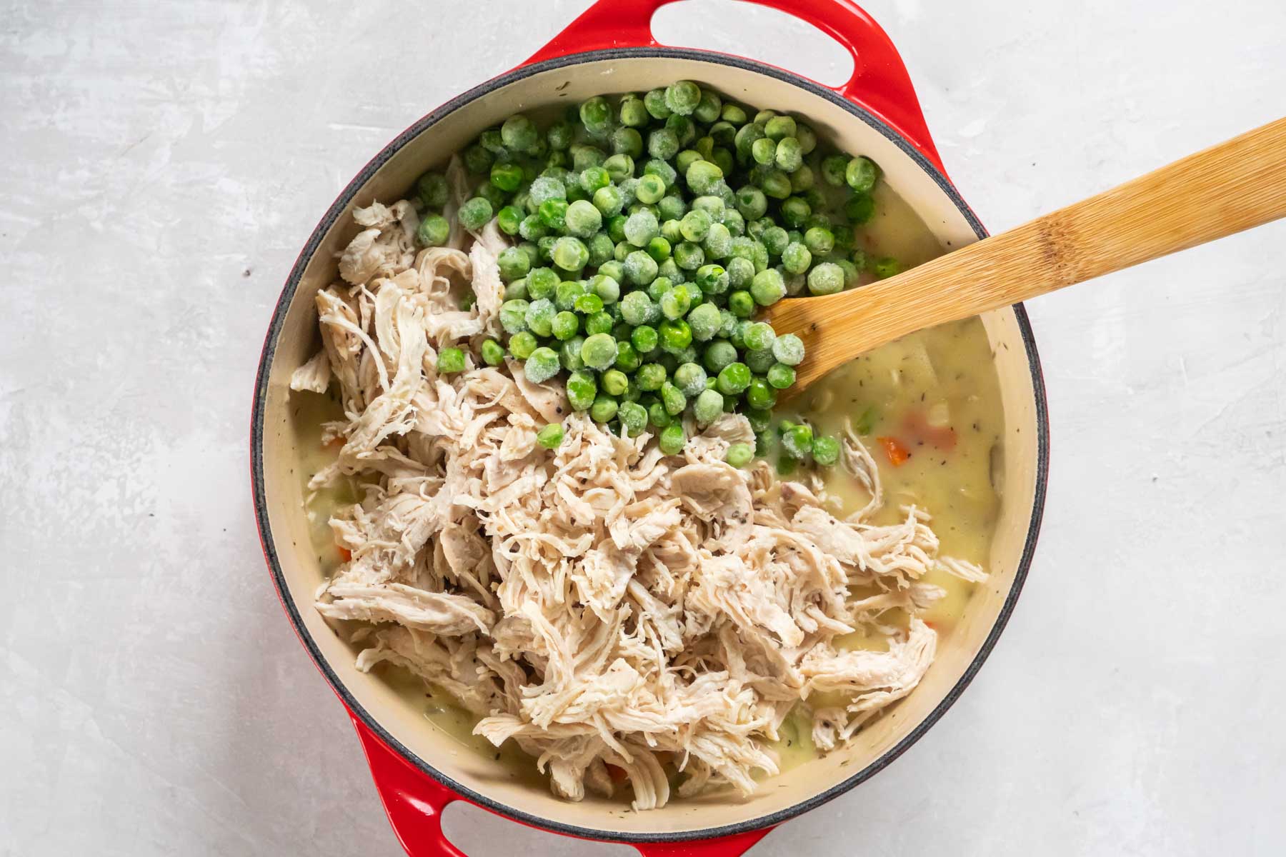 Shredded chicken and frozen peas added to filling in pot.