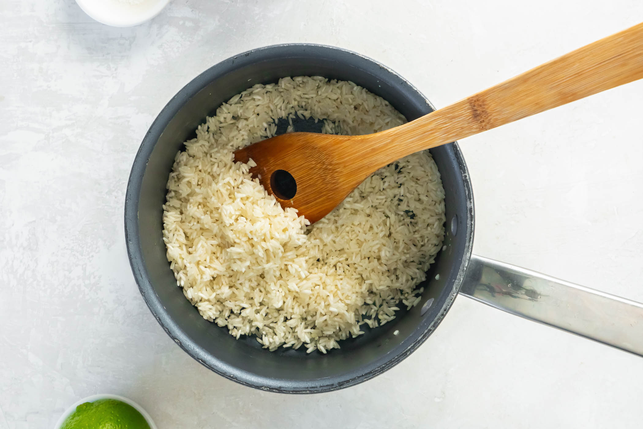 Toasting rice and garlic in a small saucepan with wooden spoon for stirring.