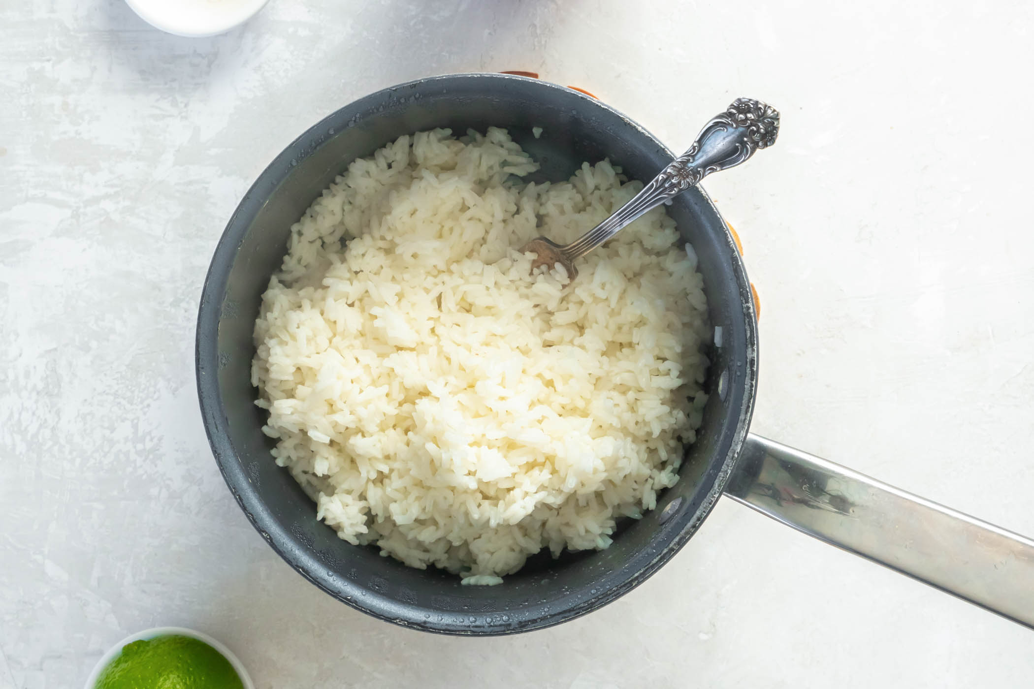 Fluffing cooked rice in pot with a fork.