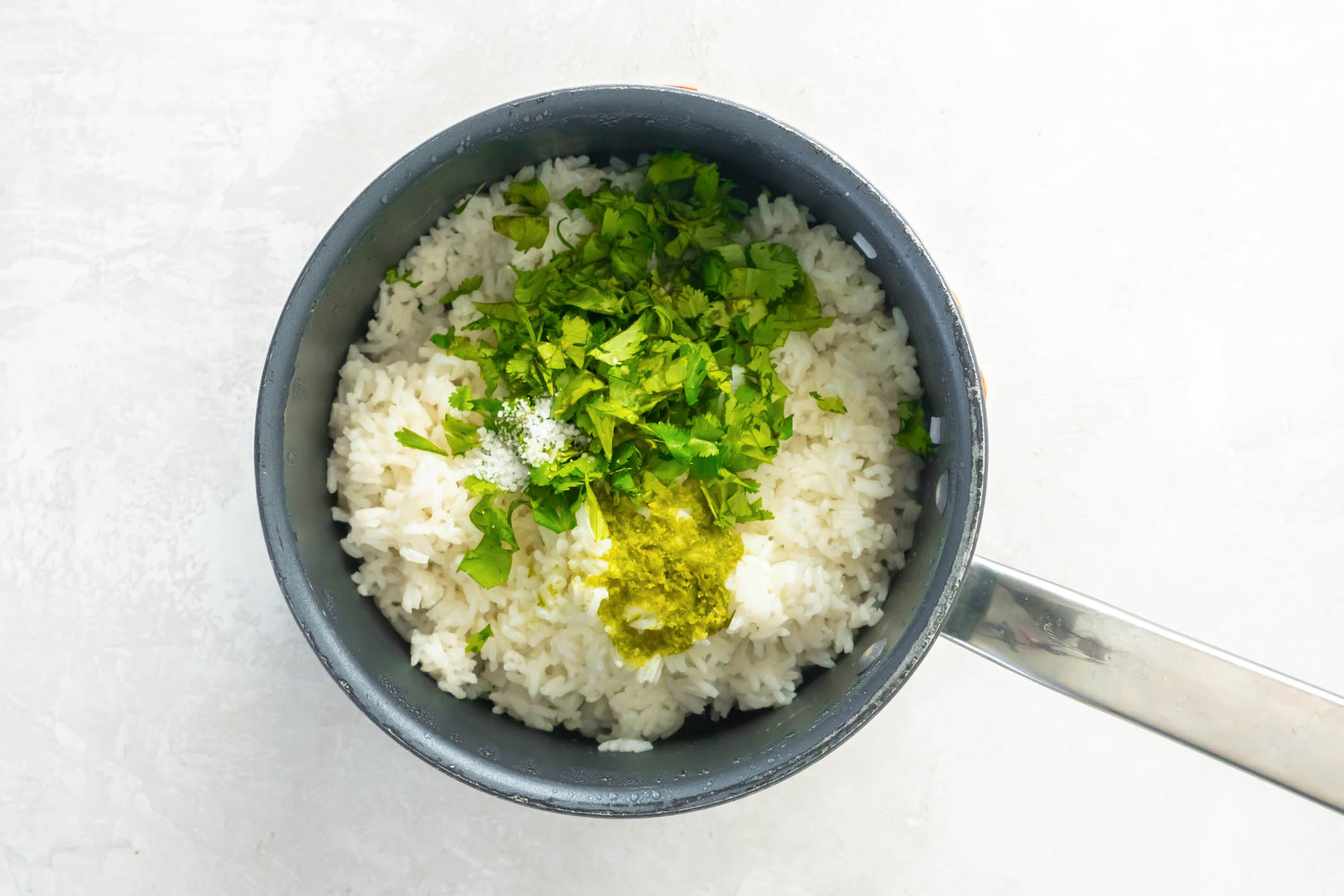 Chopped cilantro, lime zest, lime juice and salt added to cooked rice in pan.