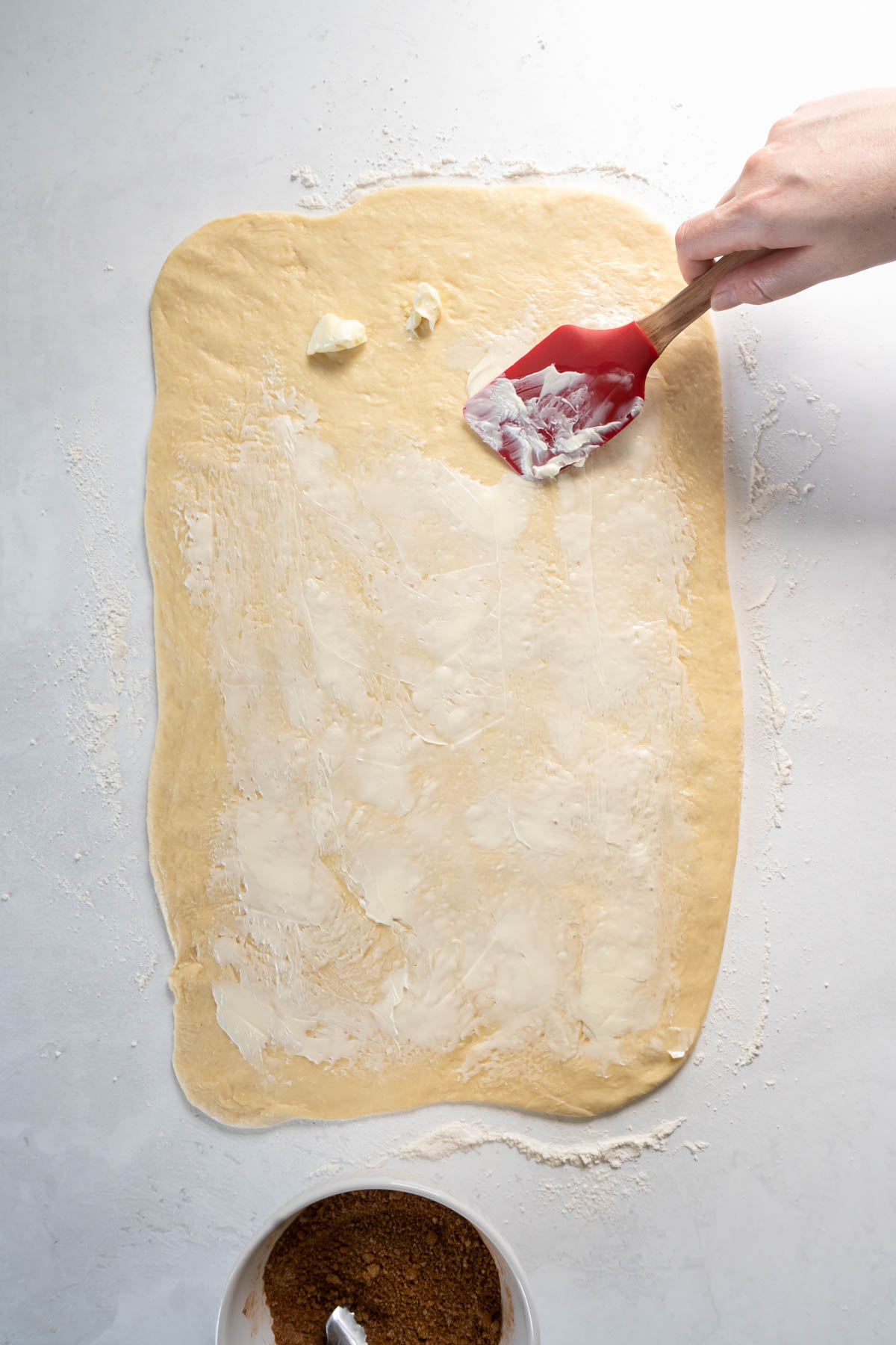 Spreading butter on rolled out dough rectangle.