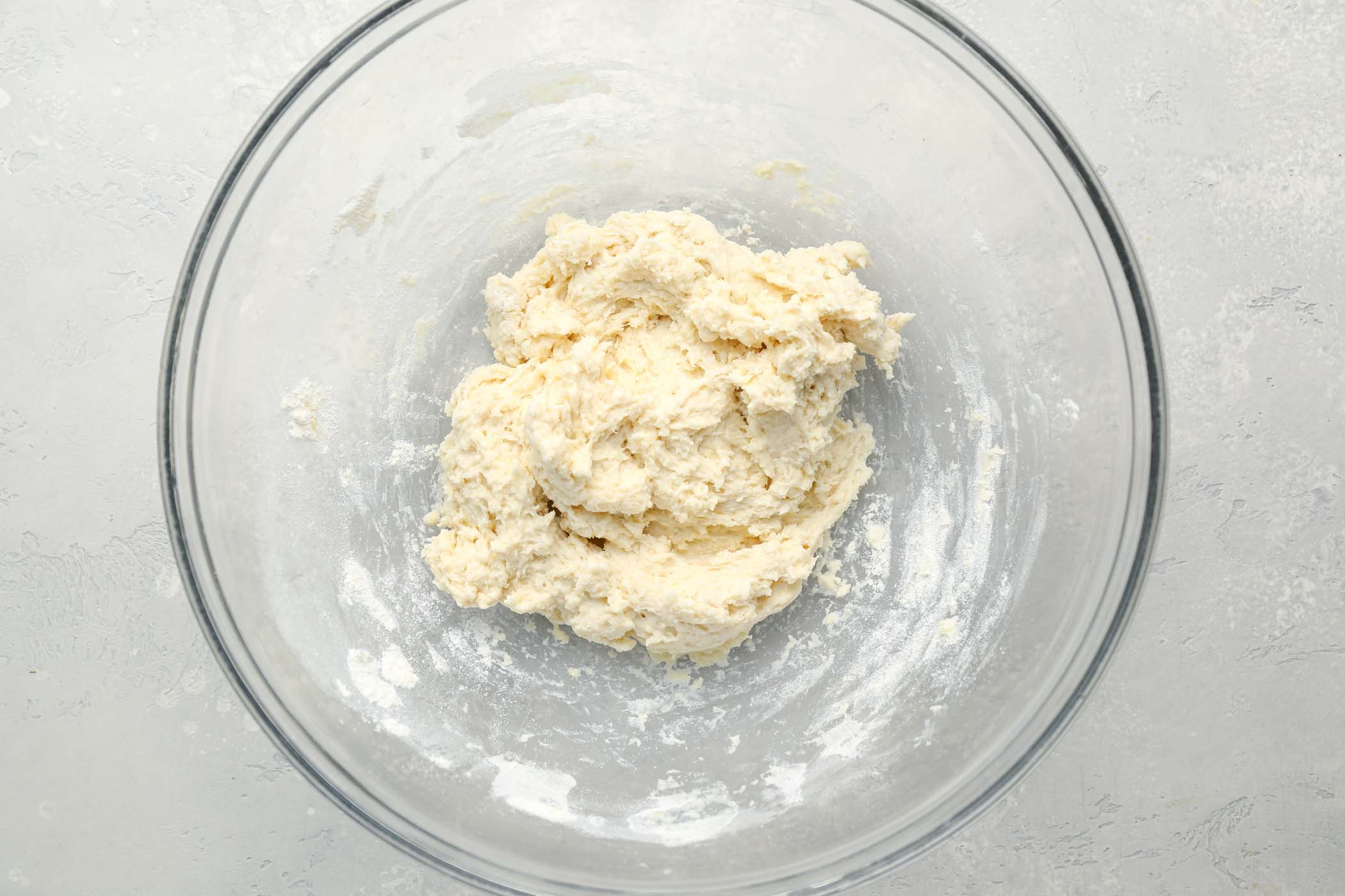 Dumpling dough in a glass mixing bowl.