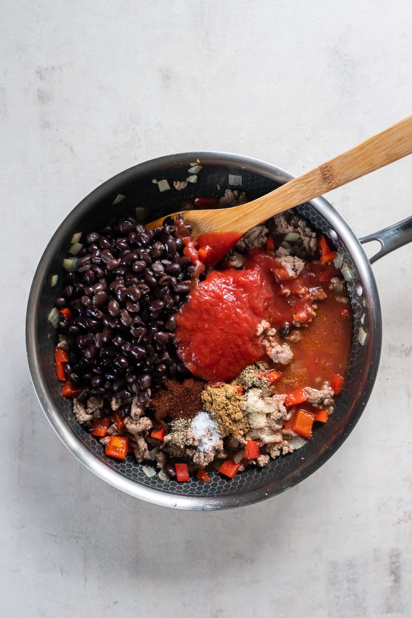 Black beans, tomato sauce, water and seasonings added to skillet with browned ground turkey, peppers and onions.