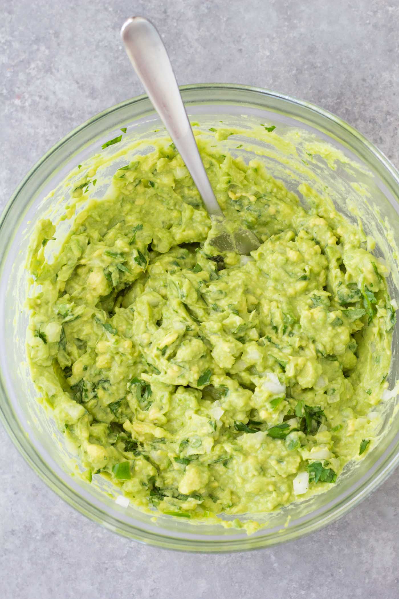 Guacamole in mixing bowl with spoon.