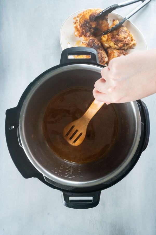 Scraping up browned bits from bottom of pot with wooden spoon.