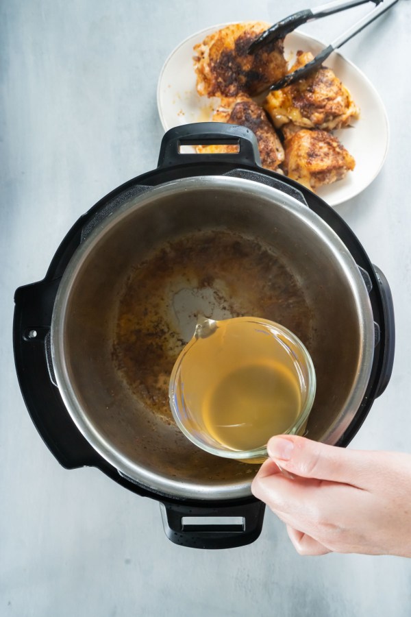 Pouring chicken broth into instant pot.