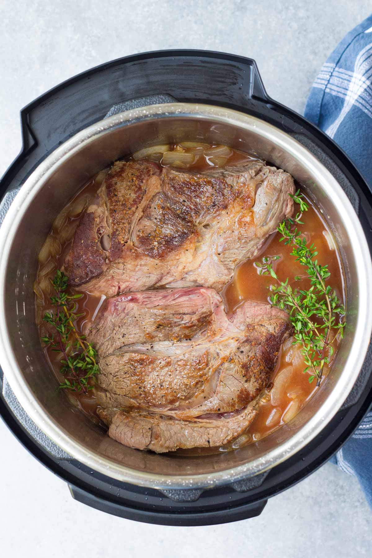 Beef and other ingredients in the instant pot before pressure cooking.