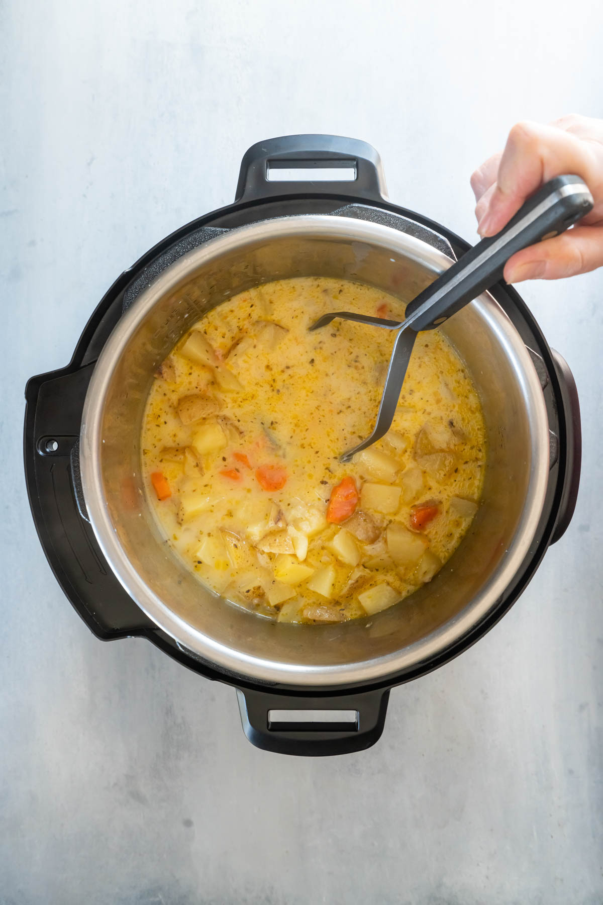 Mashing soup with potato masher.