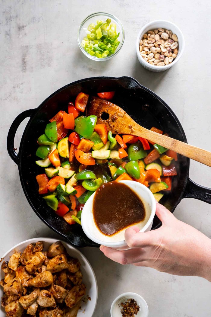 Pouring sauce into skillet with vegetables.