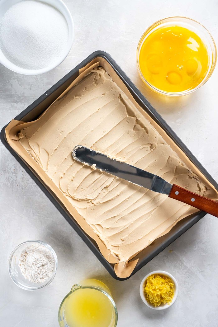 Unbaked shortbread crust in baking pan with an offset spatula.