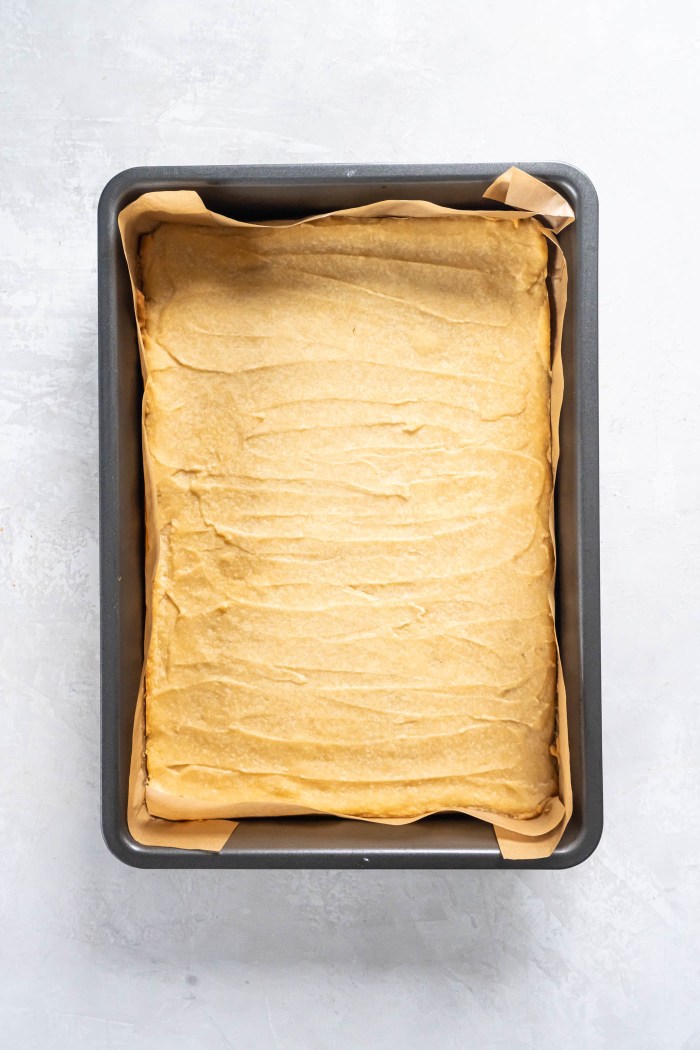 Baked shortbread crust in a parchment paper lined metal baking pan.