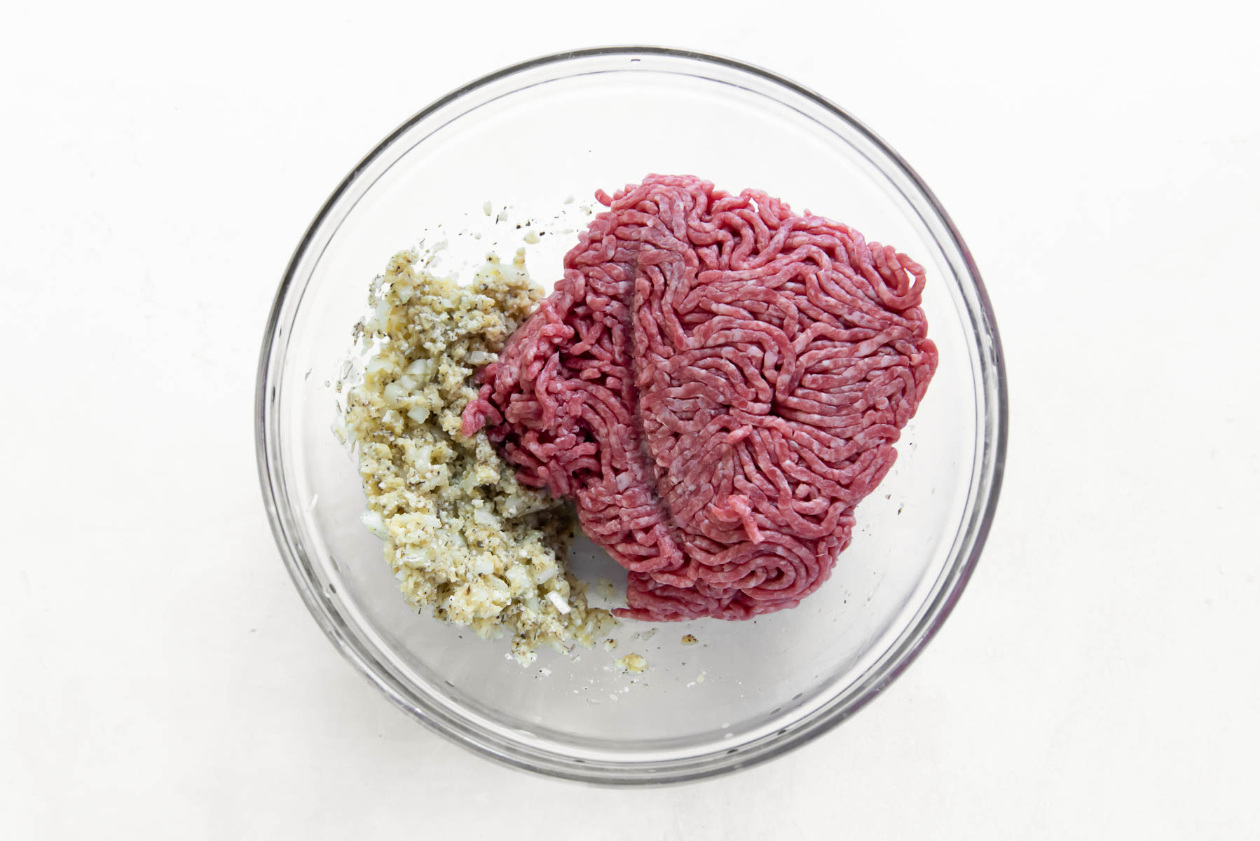 ground beef and other meatball ingredients in a glass bowl