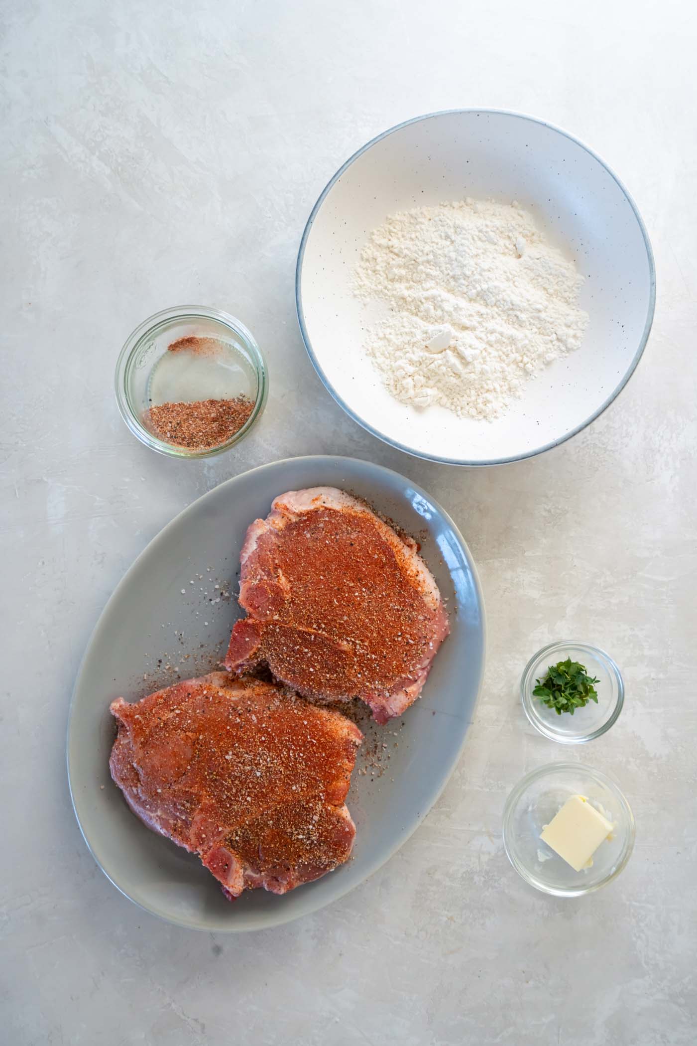 Seasoning two bone-in pork chops.