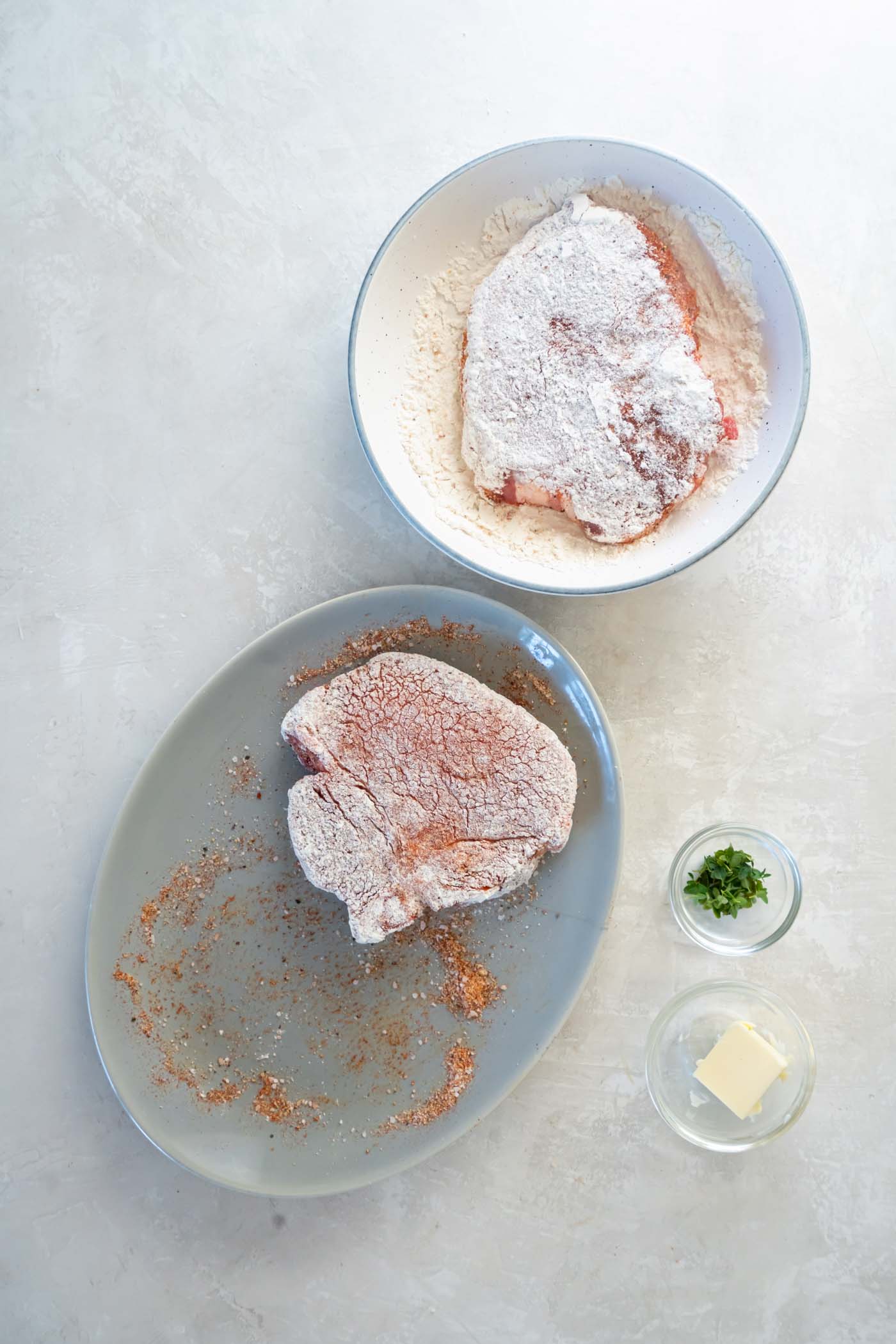 Dredging seasoned pork chops in flour.