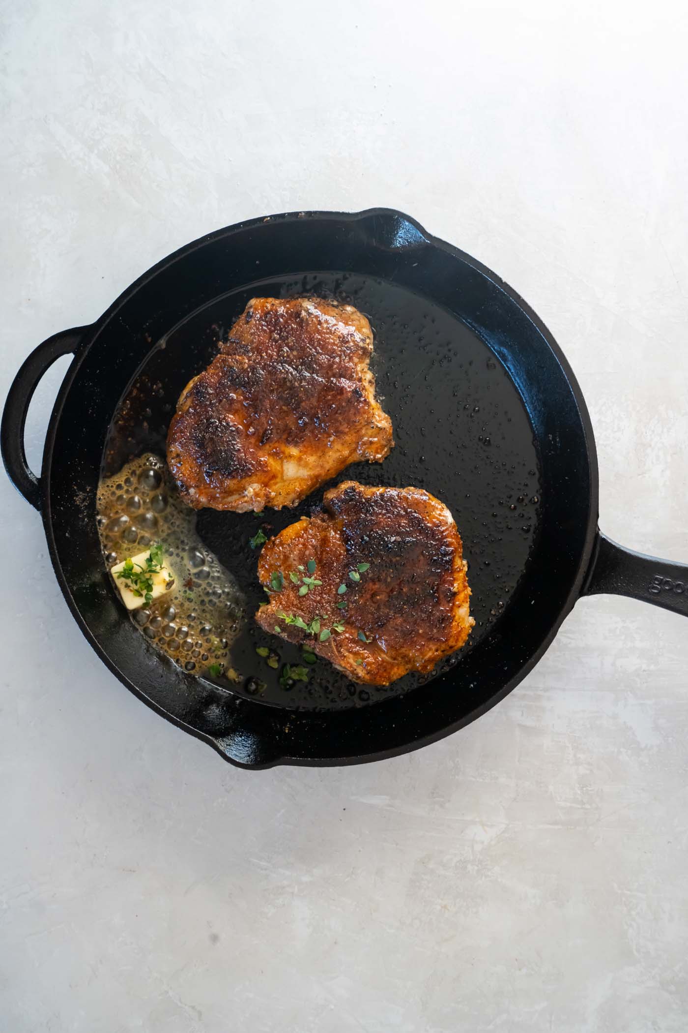 Butter and fresh thyme added to skillet with pan fried pork chops.