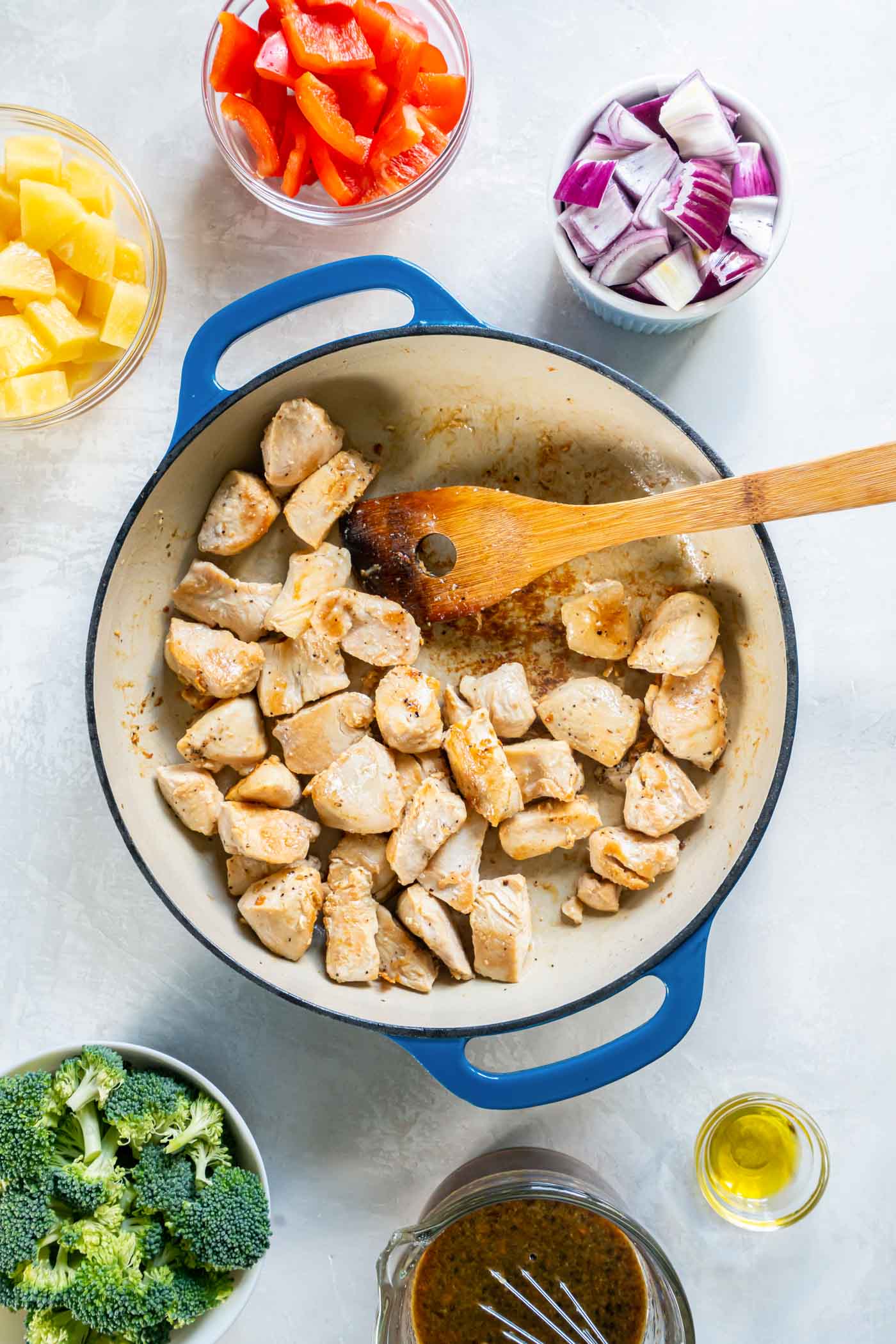 Browning chicken breast pieces in pan with wooden spoon.
